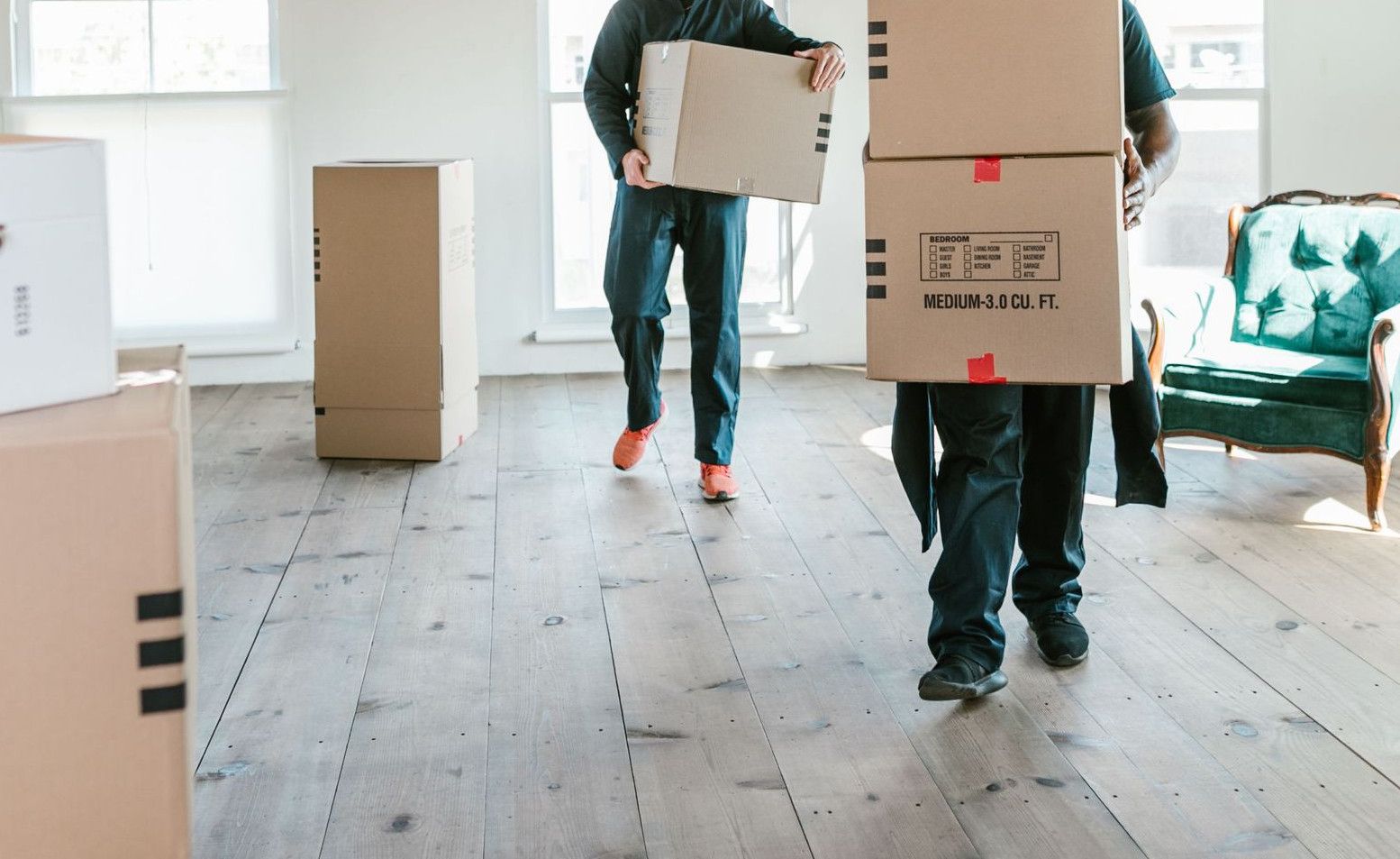 Two movers carrying boxes in a sunlit room, ready to assist with relocation.